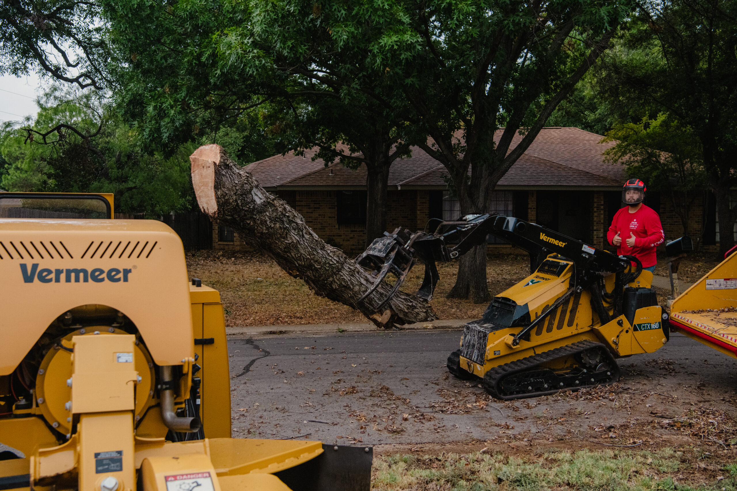 a man operating a Vermeer CTX160 skid steer to remove a large tree branch